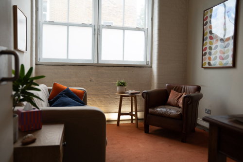 A therapist's consulting room with an armchair and a sofa.